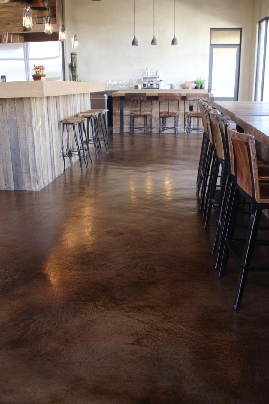 Rustic modern café interior with polished concrete floors and wooden bar stools.