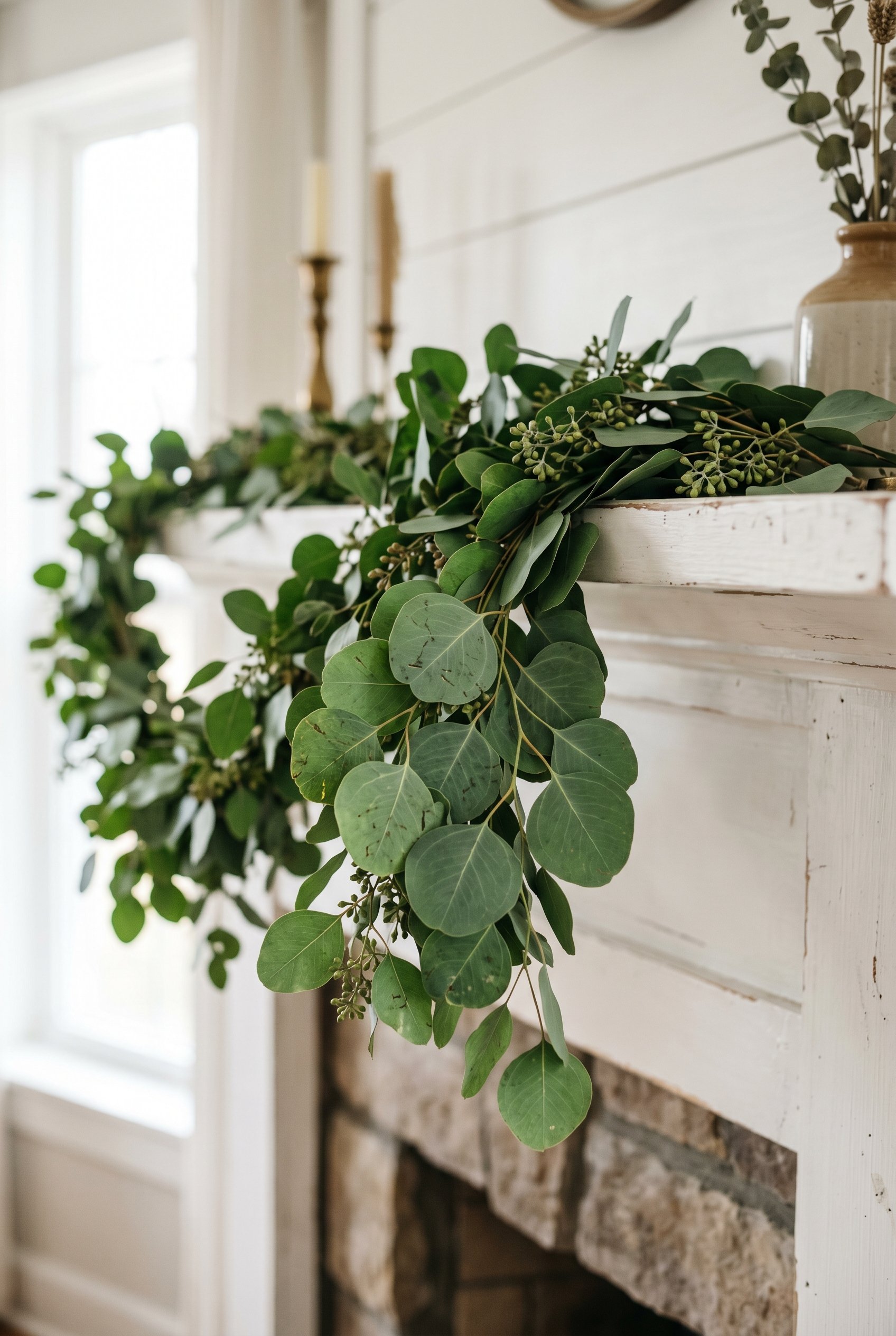 Photorealistic interior photo. Close up of a lush green eucalyptus garland draped over a white wood mantel, suspended invisibly. Natural daylight, soft shadows, macro lens depth of field. Editorial ph