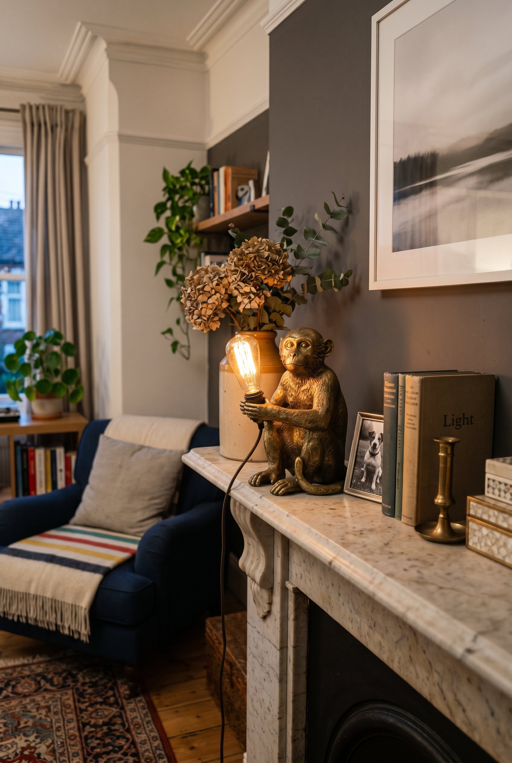 Photorealistic interior photo. Solid brass monkey figurine holding a glowing Edison lightbulb, sitting on a marble mantle, sharp focus, moody lighting. Editorial photography style, no people visible.